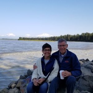 couple sitting on rocks in front of bay in alaska